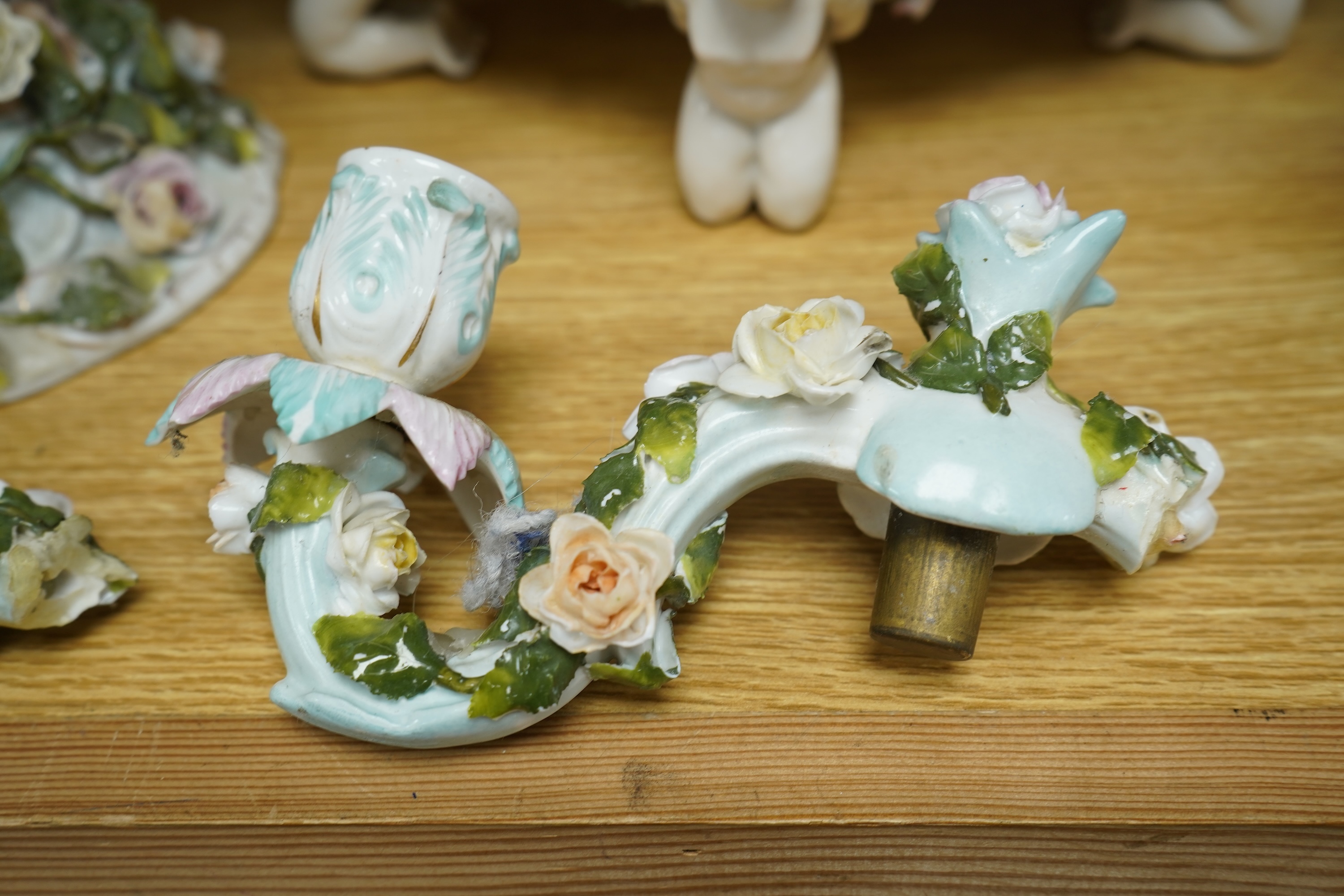A German flower encrusted porcelain figural candelabrum, 30cm high, a cherub jardiniere and a cherub vase, all encrusted